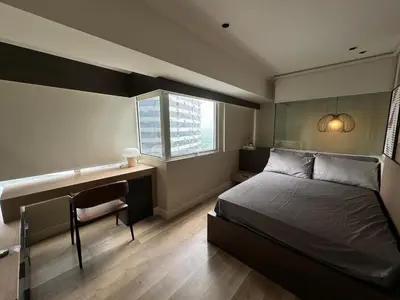 a bedroom with a bed and a desk and a window at Dazzling fully furnished unit BGC w Pool in Manila