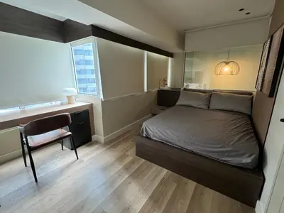 a bedroom with a bed and a desk and a window at Dazzling fully furnished unit BGC w Pool in Manila