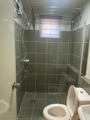 a bathroom with a shower with a toilet and a sink at Kral Suite in Las Piñas in Manila