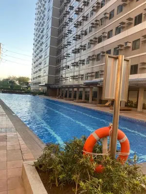a swimming pool in front of a large building at Beans Crib Staycation at SMDC Green 2 Residences in Dasmariñas