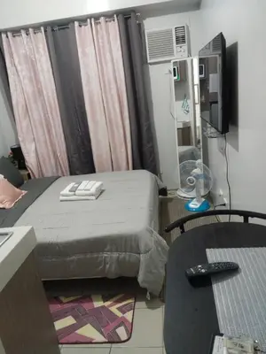 a room with a bed and a desk and a tv at Nice condotel in Manila
