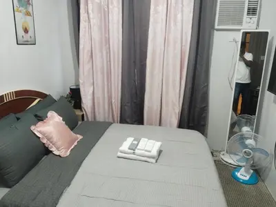 a bedroom with a bed with a fan at Nice condotel in Manila