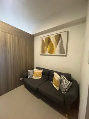 a living room with a black couch with pillows at Fame Residences EDSA Shaw MRT Shangrila Megamall in Manila