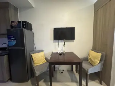 a dining room with a table and a refrigerator at Fame Residences EDSA Shaw MRT Shangrila Megamall in Manila