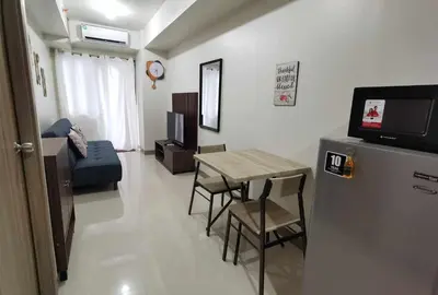 a small living room with a table and a television at S Residences in Manila
