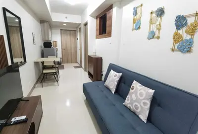 a living room with a blue couch and a table at S Residences in Manila