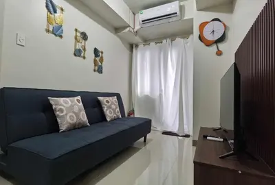 a living room with a blue couch and a clock at S Residences in Manila