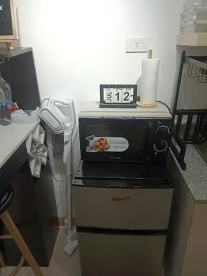 a kitchen with a clock on top of a microwave at La Maison d'Antoine in Manila