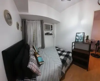 a bedroom with a bed with pillows and a window at Condo In Manila in Manila