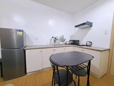 a small kitchen with a table and a refrigerator at Grace Tower 3 in Manila