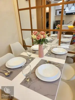 a table with plates and glasses and a vase of flowers at SleepScape Staycation in Manila