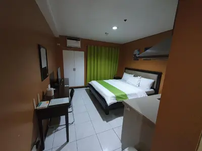 a bedroom with a bed and a desk and a green curtain at Travel time suites bel air soho in Manila