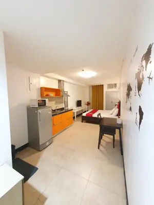 a living room with a kitchen with a table and a refrigerator at Travel time suites bel air soho in Manila