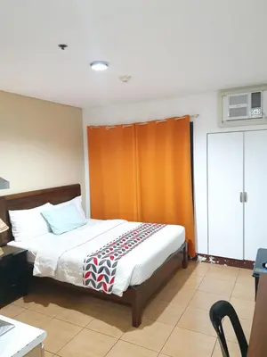a bedroom with a bed with an orange curtain at Travel time suites bel air soho in Manila