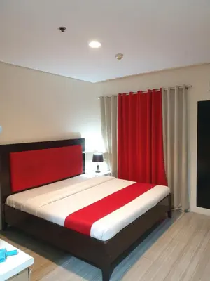 a bedroom with a bed with a red curtain at Travel time suites bel air soho in Manila