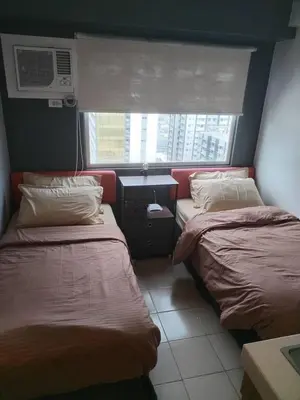 two beds in a small room with a window at Affordable Studio 2 Twin Beds - City View EDSA in Manila