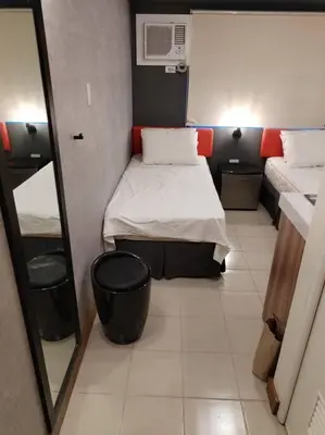a small room with two beds and a mirror at Affordable Studio 2 Twin Beds - City View EDSA in Manila