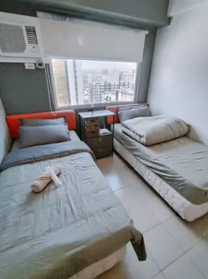 two beds in a room with a window at Affordable Studio 2 Twin Beds - City View EDSA in Manila