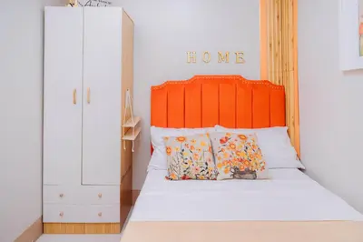 a bed with an orange headboard and some pillows at Oranje Suite near NAIA AIRPORT in Manila