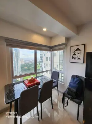 a dining room with a table and chairs and a large window at Fort Victoria Tower B Condo BGC, Taguig City in Manila