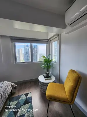 a bedroom with a yellow chair and a window at Fort Victoria Tower B Condo BGC, Taguig City in Manila
