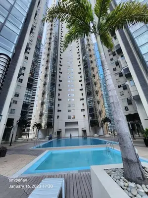 a large apartment building with a swimming pool and a palm tree at Fort Victoria Tower B Condo BGC, Taguig City in Manila