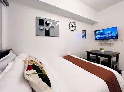 a bedroom with a bed and a flat screen tv at 1BR Condotel with Balcony at SM Light Residences #LT01 in Manila