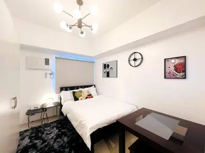 a white bedroom with a bed and a table at 1BR Condotel with Balcony at SM Light Residences #LT01 in Manila
