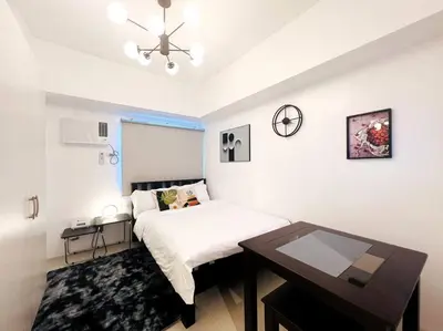 a white bedroom with a bed and a table at 1BR Condotel with Balcony at SM Light Residences #LT01 in Manila