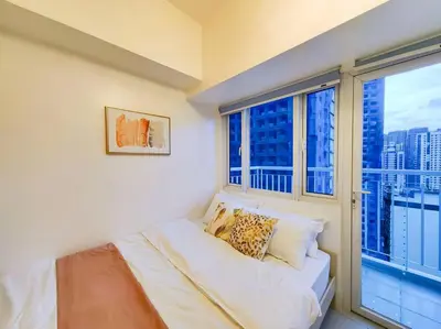 a bedroom with a large window and a bed with pillows at 1BR Condotel with Balcony at SM Light Residences #LT03 in Manila