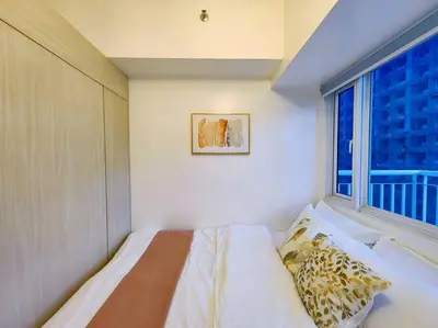 a bedroom with a bed and a large window at 1BR Condotel with Balcony at SM Light Residences #LT03 in Manila