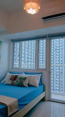 a bedroom with a blue bed and two windows at 1BR Condotel with Balcony at SM Light Residences #LT04 in Manila