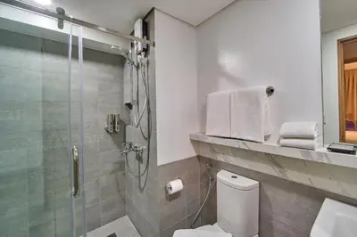 a bathroom with a shower and a toilet at The Connor Serviced Residences Managed by HII in Manila