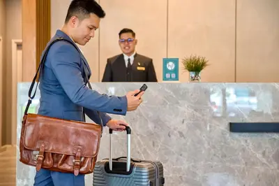 a man with a suitcase looking at his cell phone at The Connor Serviced Residences Managed by HII in Manila