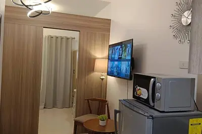 a room with a microwave on top of a refrigerator at 1BR Condotel with Balcony at FAME Residences #FM01 in Manila