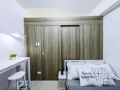 a bedroom with a bed with a wooden wall at 1BR Condotel with Balcony at FAME Residences #FM01 in Manila