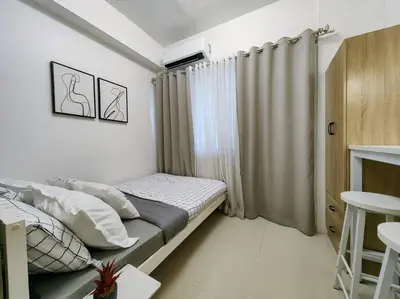 a small bedroom with a bed and a table at 1BR Condotel with Balcony at FAME Residences #FM01 in Manila