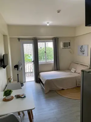 a bedroom with a bed and a table in a room at Studio-type Apartment near Manila International Airport in Manila