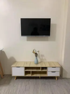 a tv on a wall with a vase of flowers on a table at Studio-type Apartment near Manila International Airport in Manila