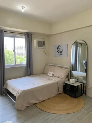 a bedroom with a large bed and a mirror at Studio-type Apartment near Manila International Airport in Manila