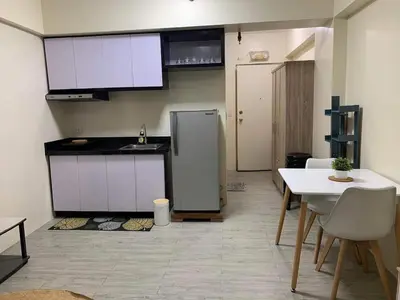 a kitchen with a refrigerator and a table and chairs at Studio-type Apartment near Manila International Airport in Manila