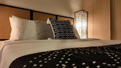 a bedroom with a large bed with pillows at NITO Modern Philippine Styled Home at Jazz Residences Makati in Manila