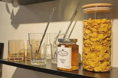 a shelf with glasses and a jar of honey at NITO Modern Philippine Styled Home at Jazz Residences Makati in Manila