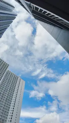 two tall buildings and a blue sky with clouds at NITO Modern Philippine Styled Home at Jazz Residences Makati in Manila