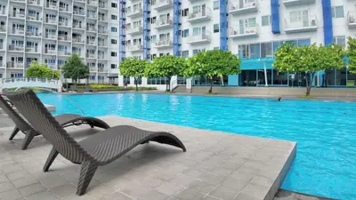 a swimming pool with two chairs next to a building at NITO Modern Philippine Styled Home at Jazz Residences Makati in Manila