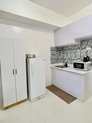 a white kitchen with a refrigerator and a sink at Serene Condo Unit in Front of US Embassy in Manila