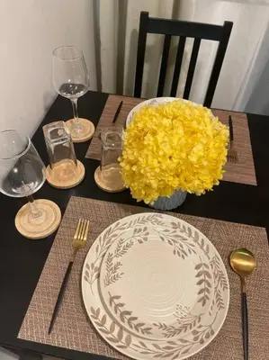 a table with a white plate and a vase of yellow flowers at Casa Del Castillo at Fame Residences near Megamall in Manila