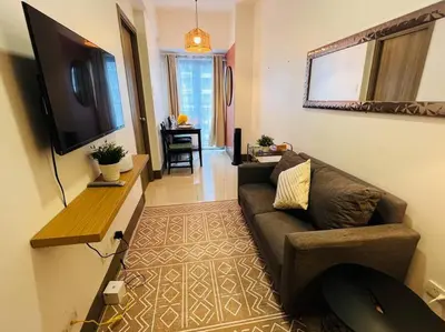 a living room with a couch and a flat screen tv at Casa Del Castillo at Fame Residences near Megamall in Manila