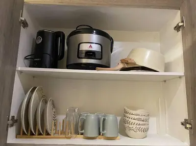a cupboard with a coffee pot and plates and cups at Casa Del Castillo at Fame Residences near Megamall in Manila