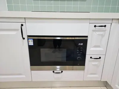 a microwave in a kitchen with white cabinets at The Infinity Towers in BGC - Spectacular 2BR near Hight Street in Manila